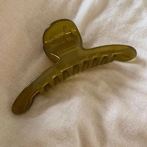 Pince à cheveux translucide vert olive en résine pour femme sur fond en tricot beige