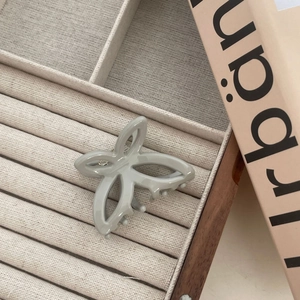 Détail de la pince papillon sur une boîte à bijoux en velours beige sous une lumière douce