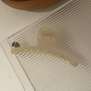 Détail de la pince à cheveux en résine crème translucide avec dents sur acrylique