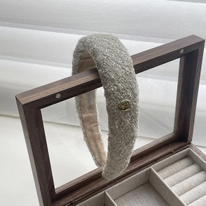 French tweed sponge headband with gold metallic badge on a vintage wooden jewelry box