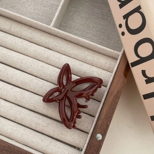 Détail de la pince à cheveux papillon bordeaux sur un tissu en velours beige doux