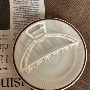 Minimalist cream white large metal paint shark hair claw clip in a ceramic dish