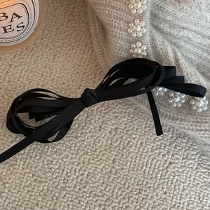 Elegant black multi-layered ribbon bow hair clip on a vintage grey knitted sweater fabric