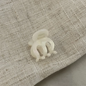 Detail view of mini creamy acetate hair claw with France Handmade gold lettering