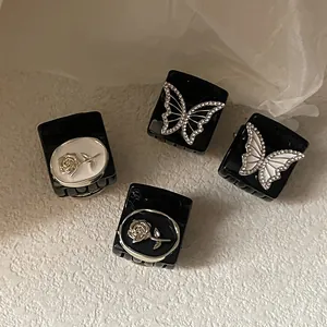 Detail view of black acrylic hair clips with silver rose and butterfly crystal accents