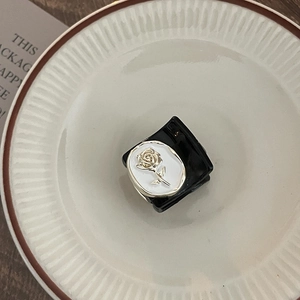 Close-up of black square hair claw with silver rose relief on a ceramic plate