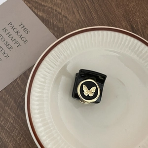 Detail view of small black hair claw clip with golden butterfly design on ceramic tray