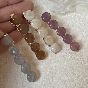 Détail de quatre barrettes à cheveux avec perles marbrées en gris, marron, blanc et violet