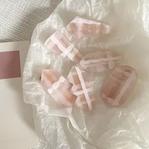 Detail view of 5-piece pink jelly hair clips with white wave patterns on soft fabric
