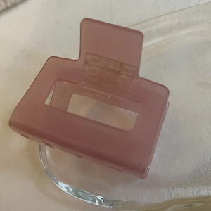 Détail d'une pince à cheveux en acétate rose poudré avec design rectangulaire et ressort doré