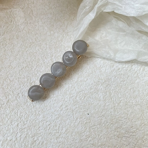 Zoom sur une barrette à cheveux bec de canard avec perles marbrées grises sur métal doré