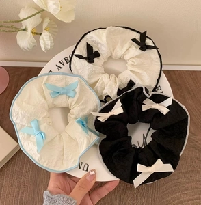 Close-up of three sweet scrunchies with elegant bow ties and pleated texture on a tray