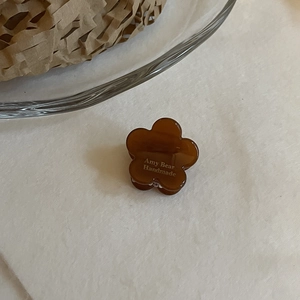 Détail de la mini pince à cheveux fleur en acétate ambre foncé avec logo fait main