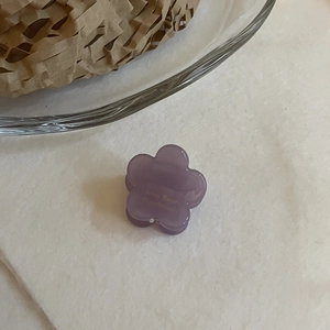Gros plan d'une petite pince à cheveux violette en forme de fleur avec texture résine
