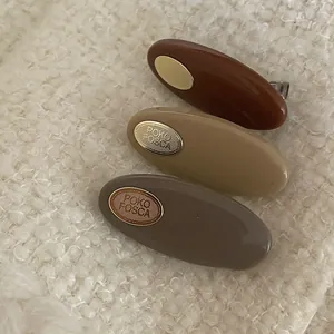 Detailed view of three earthy tone resin hair clips with gold metal plates on knit fabric