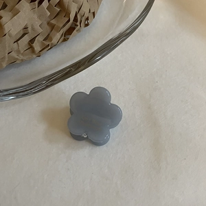 Gros plan d'une mini pince à cheveux fleur bleu Morandi sur une surface minimaliste
