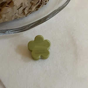 Vue détaillée d'une petite pince à cheveux fleur verte en acétate au fini brillant