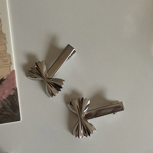 Detalle macro de dos pinzas para el cabello de metal plateado con forma de Farfalle