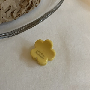 Détail macro de la pince à cheveux fleur jaune avec texte Amy Bear Handmade sur les pétales