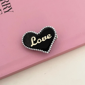 Roze hart haarspeld met witte parels en gouden Love belettering op een roze boekbasis