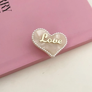 Roze hartvormige haarklem met marmerhars, parels en goudkleurige Love-belettering