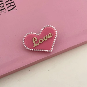 Macro-opname van roze hartvormige haarspeld met witte parels en gouden Love-tekst