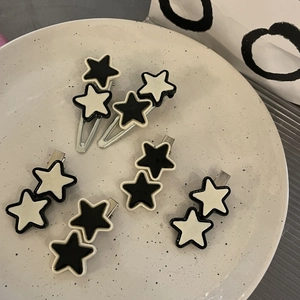 Set of six Y2K star hair clips in black and white colors on a ceramic tray