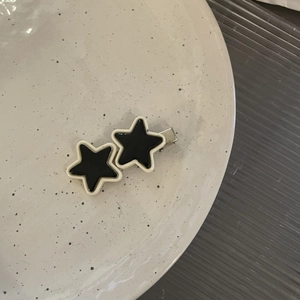 Detail of Y2K black double star hair clip with white borders on a ceramic plate