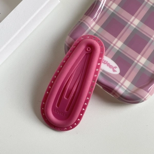Close-up of pink matte hair clip with Lovely engraving and decorative hole pattern