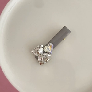 Haarklammer mit rosa Strass-Herz und silbernem Bären-Detail in einer weißen Schale