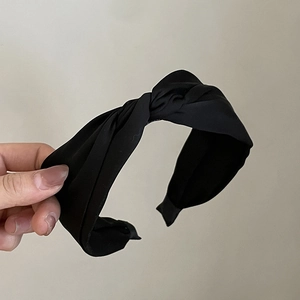 Close-up of black matte fabric headband with elegant cross-knot design and knit texture