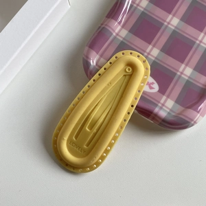 Detail of yellow silicone water drop hair clip with LOVELY engraving and hollowed edge