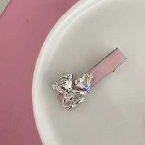 Rosa Herz-Haarklammer mit Strasssteinen und Silberbär auf einem weißen Teller