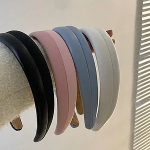 Minimalist padded PU leather headbands in black, pink, and blue on a white display stand