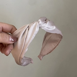 Detailed close-up of a twisted satin headband in elegant champagne pink finish