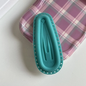 Teal oval silicone hair clip with LOVELY engraving and hollow detailing on purple plaid