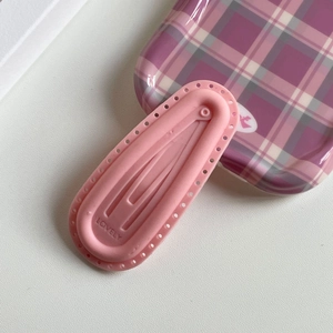 Pink silicone puff hair clip with LOVELY lettering and a drop shape on checkered tray