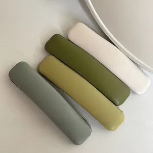 Detail view of four Morandi colored rectangular hair clips in grey, green, and cream white