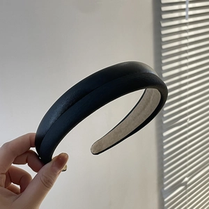 Close-up of thick black PU leather headband showing textured sponge padding and sleek finish
