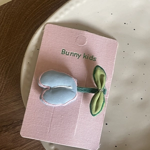 Detail view of tulip fabric hair clip for girls in blue and green on bunny kids card