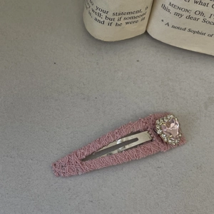 Pink heart-shaped rhinestone hair clip with lace edging on vintage book background