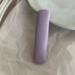 Detail shot of a light purple leather-textured rectangular hair clip on white paper