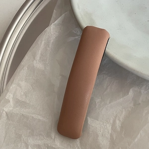 Detail of pink-brown leather hair clip with lychee texture on white wrinkled paper