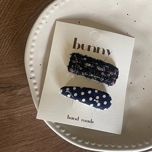 Detail of handmade bow hair clips with navy polka dots and black tweed on display card