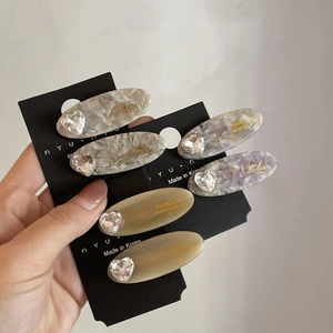 Set of six marble texture resin hair clips with heart rhinestone accents on a black card