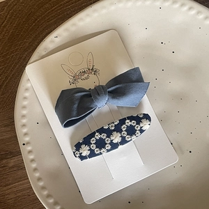 Detail of light blue bow clip and dark blue floral embroidery hair accessories set