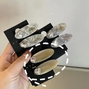 Close-up of acetate hair clips with marble texture, heart rhinestones and gold lettering