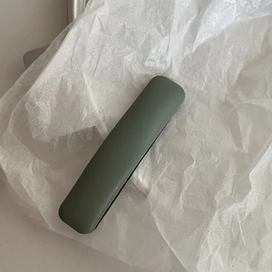Green leather protective sleeve for stylus or pens on white textured paper