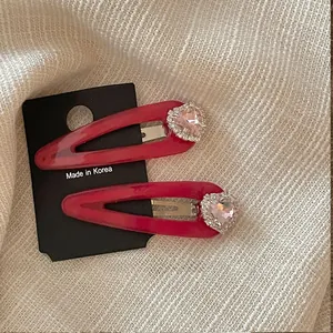 Dettaglio di fermagli per capelli con cuore di cristallo rosa e strass su carta nera