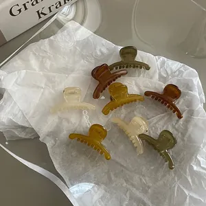 Close-up of mini hair claws in amber and earth tones on a soft textured background